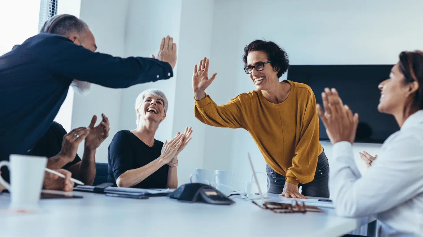 Colleagues celebrating and high-fiving in a meeting room